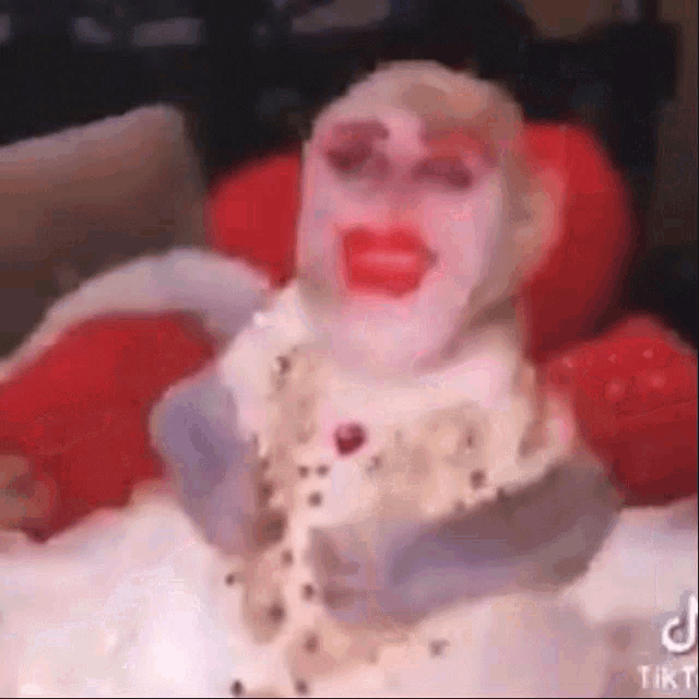 a person with a face painted like a clown is sitting on a couch .