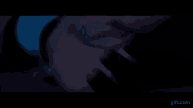 a close up of a person 's face in the dark with a blue light behind them .