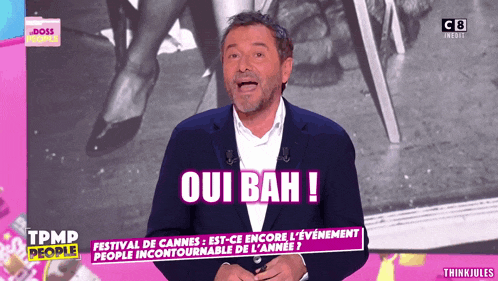 a man stands on a stage with the words oui bah in pink letters