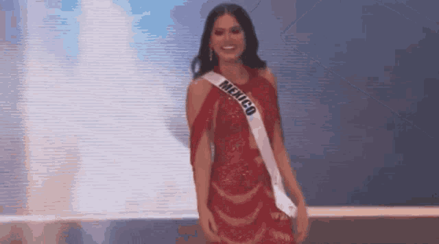 a woman wearing a red dress and a sash that says mexico is standing on a stage .