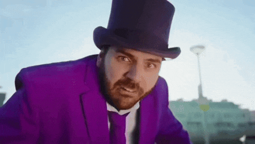 a man in a purple suit and top hat is standing in front of a building .