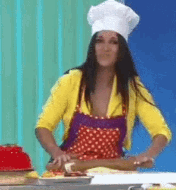 a woman in a chef 's hat and apron is rolling out dough