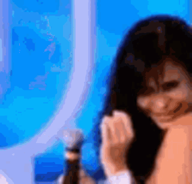a woman is sitting in front of a microphone and smiling while holding a bottle of wine .
