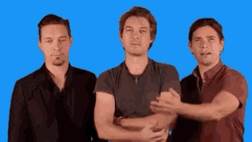 three men are standing next to each other with their arms crossed against a blue background .