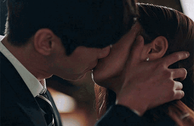a man in a suit and tie is kissing a woman