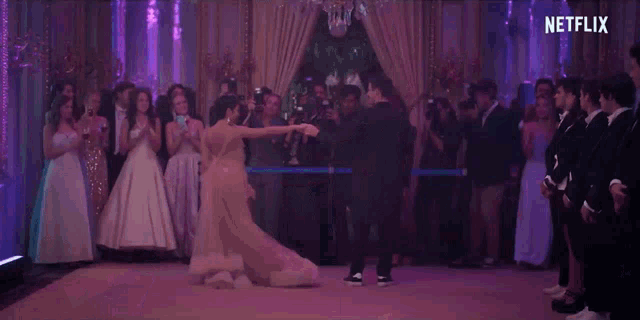 a bride and groom are dancing on a dance floor in front of a crowd of people .