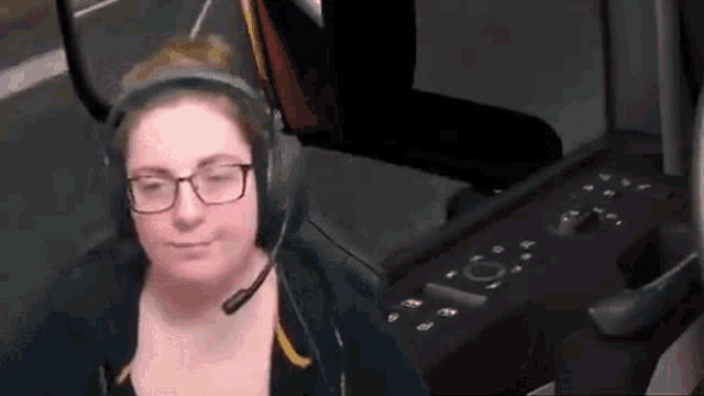 a woman wearing glasses and headphones is sitting in front of a computer .