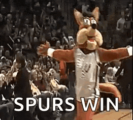 a mascot is standing on a basketball court with the words `` spurs win '' written on it .
