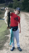 a boy in a red shirt is holding a large fish .