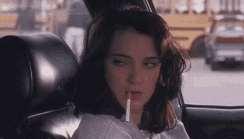 a woman is sitting in a car with a cigarette in her mouth .