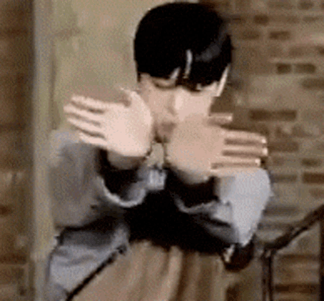 a man covering his face with his hands in front of a brick wall ..