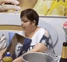 a woman is sitting at a table reading a magazine next to a bucket of champagne .