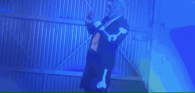 a person is holding a dumbbell in a dark room with a blue light behind them .