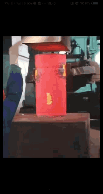 a red cylinder is being pressed by a machine on a phone screen