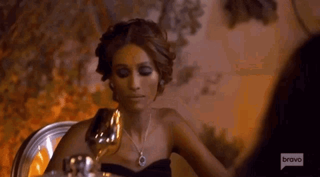 a woman is sitting at a table with a glass of wine .