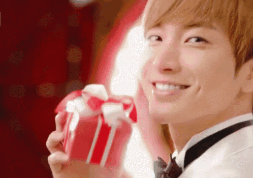 a man in a tuxedo is smiling while holding a gift box
