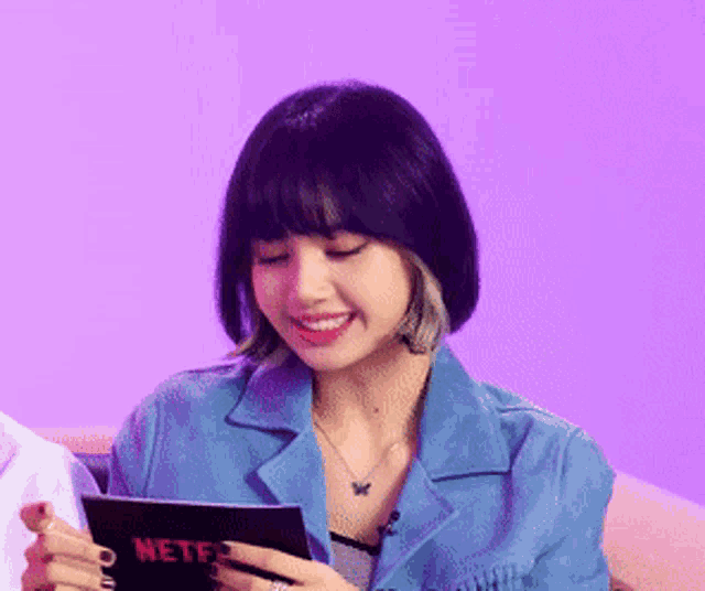 a woman in a blue jacket is holding a tablet with the word netflix on it
