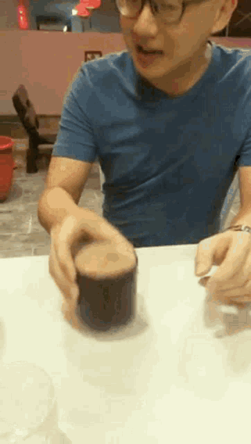 a man in a blue shirt is holding a cup of coffee