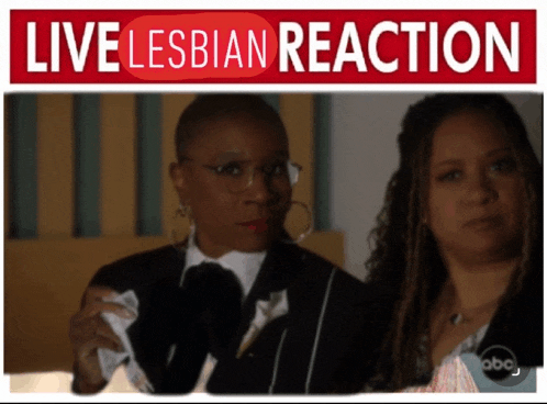 two women are standing next to each other under a live lesbian reaction banner
