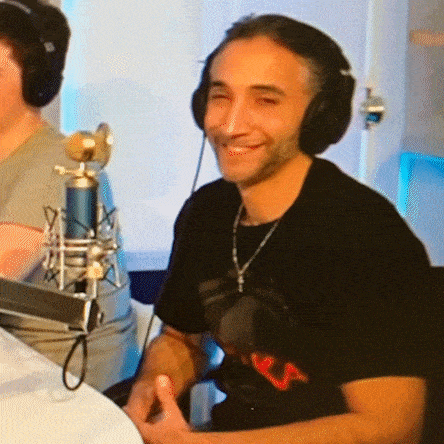 a man wearing headphones and a black shirt with the letter v on it smiles