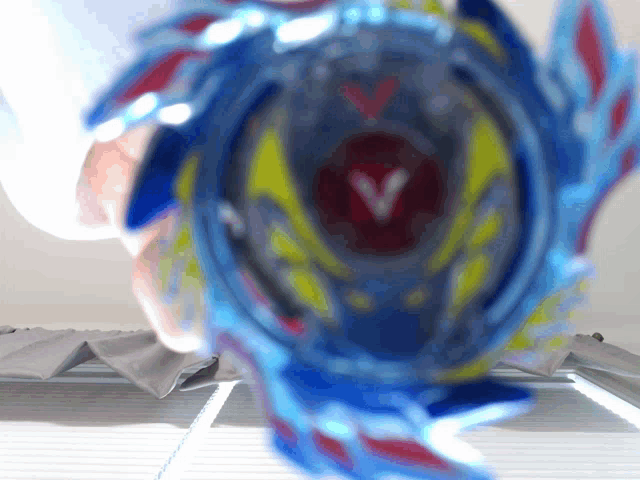 a blue spinning top with a red v on the center