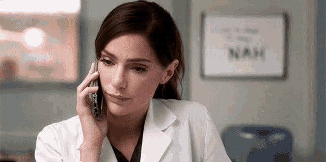 a woman in a lab coat talks on a cell phone
