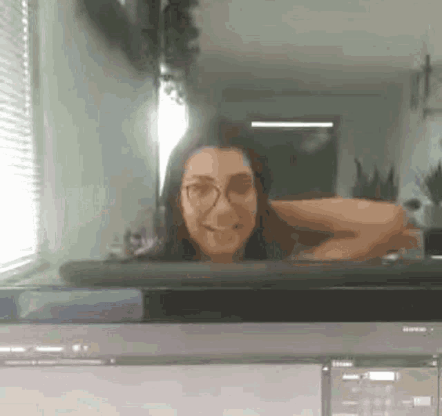 a woman wearing glasses is looking out of a microwave oven .