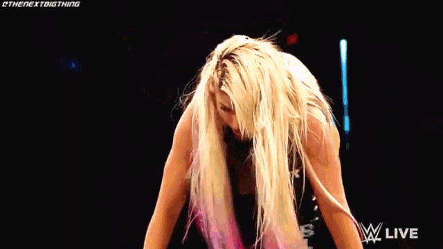 a woman with long blonde hair and pink highlights is standing on a stage .