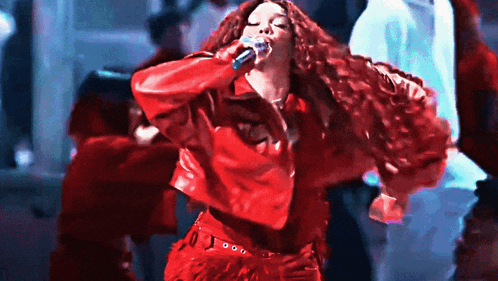 a woman singing into a microphone while wearing a red leather jacket