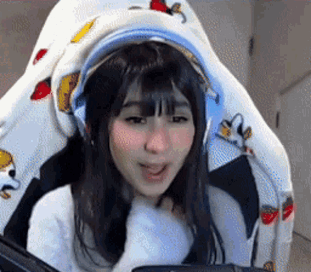 a girl wearing headphones is sitting in a chair with a blanket over her head .