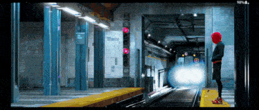 a man in a red hat is waiting for a train at a train station