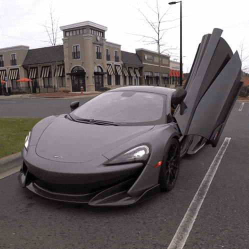 a mclaren sports car is parked in a parking lot with its doors open