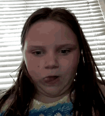 a little girl making a funny face in front of a window