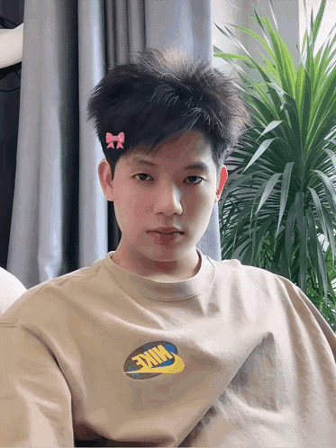 a boy with a pink bow in his hair is wearing a nike t-shirt