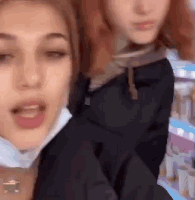two women are standing next to each other and one of them is wearing a mask on her face .