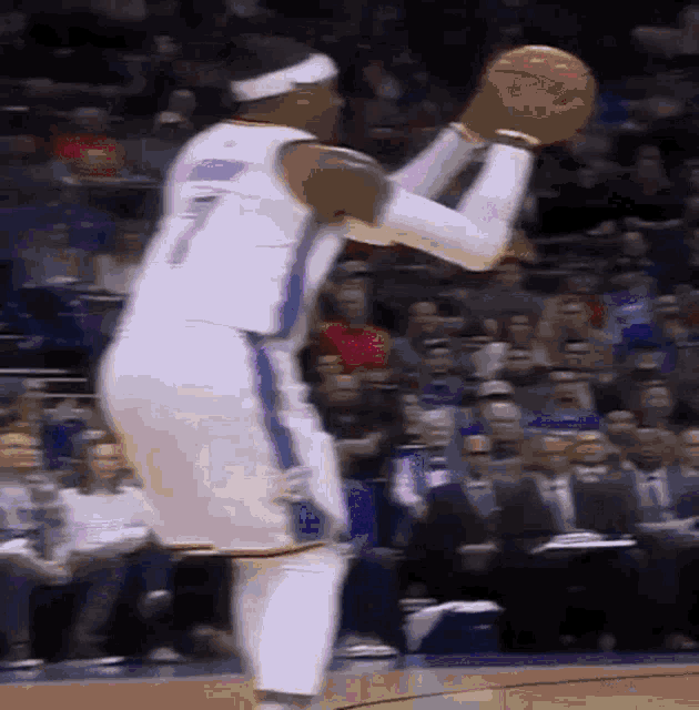 a basketball player is jumping in the air to catch a basketball during a game .
