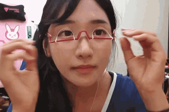 a woman wearing glasses with a sticker on the wall that says meeki
