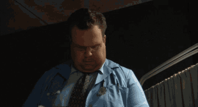 a man in a blue shirt and tie is talking about something
