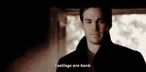 a man is standing in a dark room and says feelings are hard .