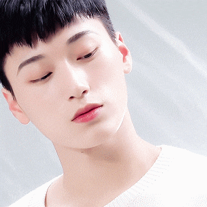 a close up of a young man 's face wearing a white shirt