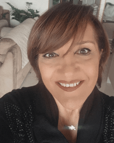 a woman is smiling and wearing a necklace that says ' emma ' on it