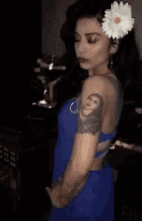a woman with a flower in her hair has a tattoo of a man on her arm