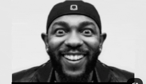 a black and white photo of a man with a beard wearing a hat making a funny face .