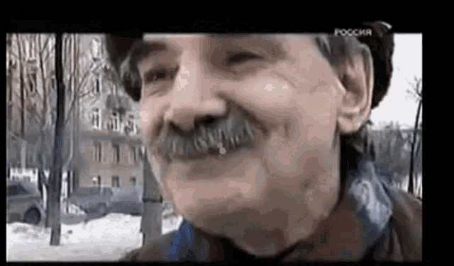 a man with a mustache is smiling and wearing a scarf around his neck .