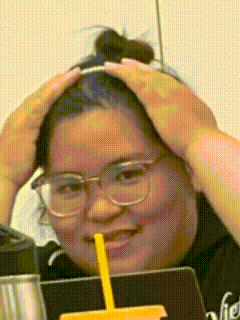 a woman with glasses and a yellow straw is smiling and holding her head