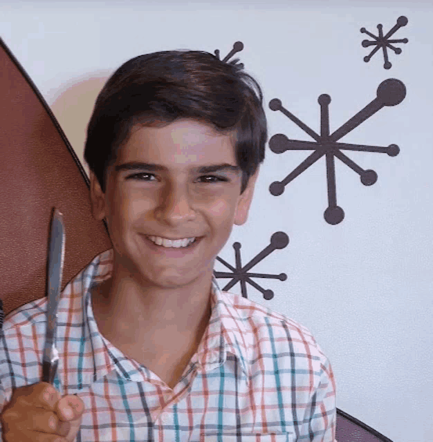 a boy in a plaid shirt is holding a knife