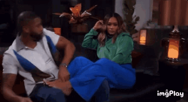 a man is tickling a woman 's feet while sitting on a couch with imgplay written in the corner