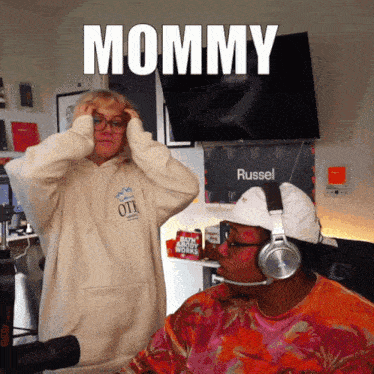 a man wearing headphones stands next to a woman wearing a hoodie that says ott on it