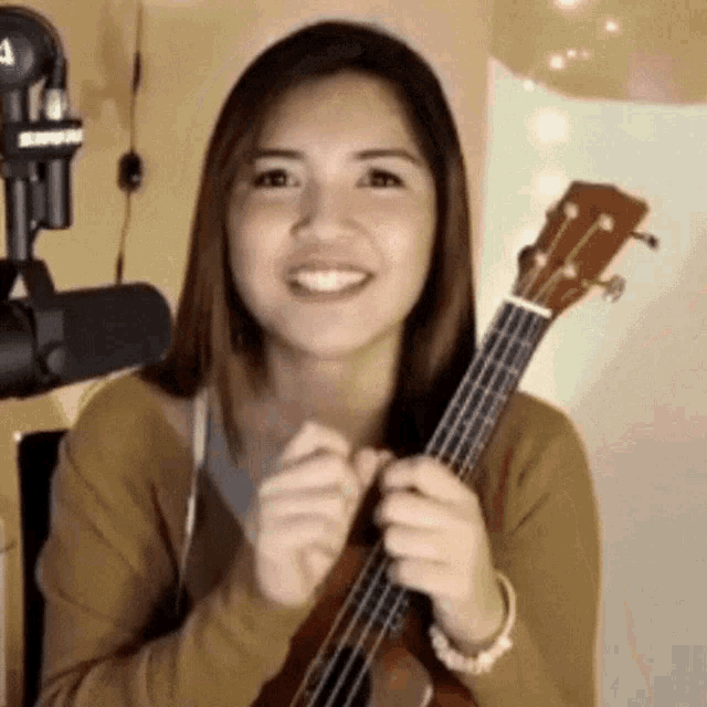 a woman is holding a guitar in front of a microphone .