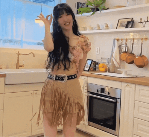 a woman in a kitchen wearing a fringe skirt